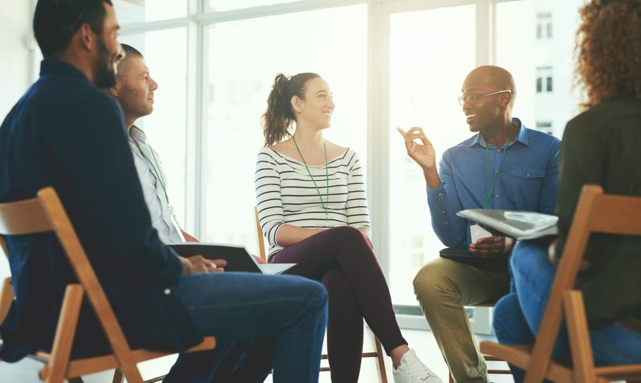 Des managers participent à un atelier de formation où ils échangent des retours constructifs autour d’une table.